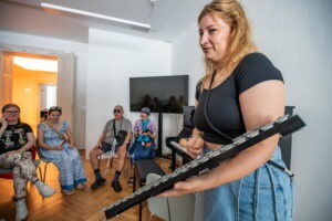 Zážitkovo – vzdelávací workshop pre nevidiacich: Dotkni sa hudby, žena ukazuje hru na malý xylofon