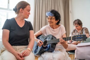 Zážitkovo – vzdelávací workshop pre nevidiacich: Dotkni sa hudby, žena hrajúca na gitaru