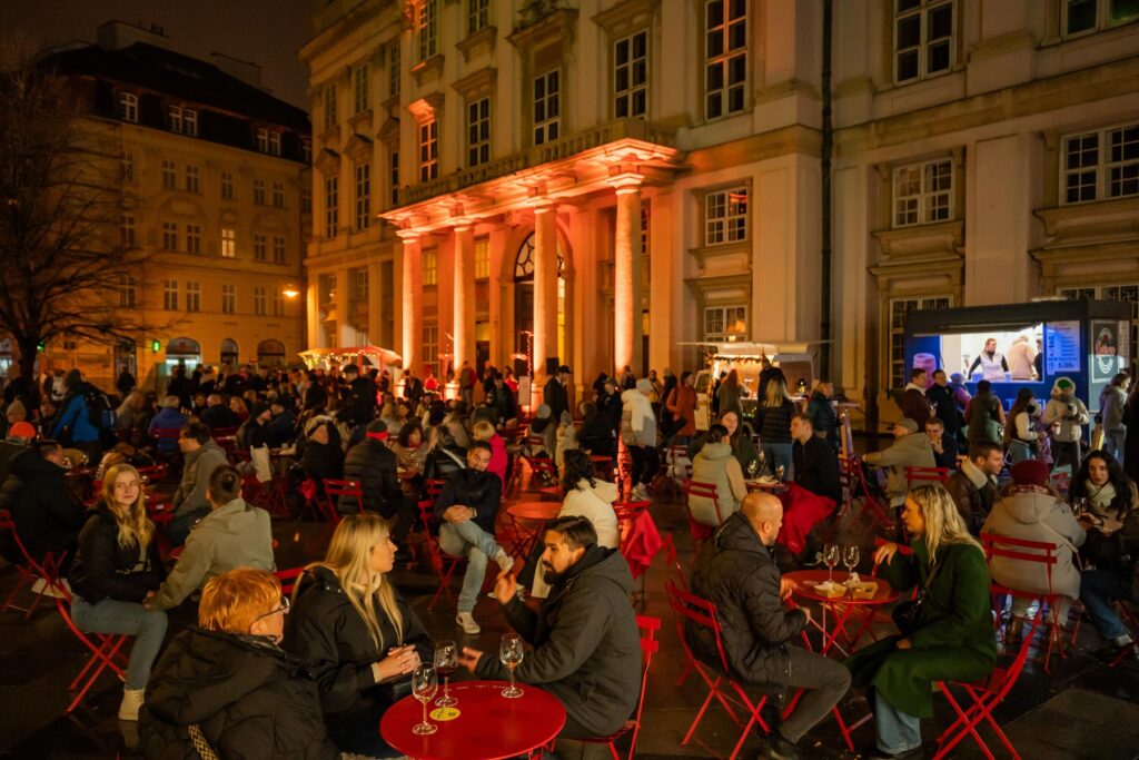 Primaciálne námestie s červenými setmi Sadni si! počas Festivalu mladého vína vo večerných hodinách
