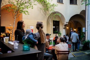 Raylab DJ Set na Bielej počas BMD 2025, návštevníci*čky sedia na červených stoličkách na nádvorí