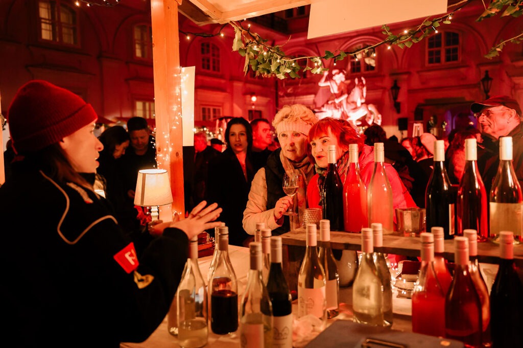 Vinárka predstavuje víno dvom starším dámam počas Festivalu mladého vína 2025