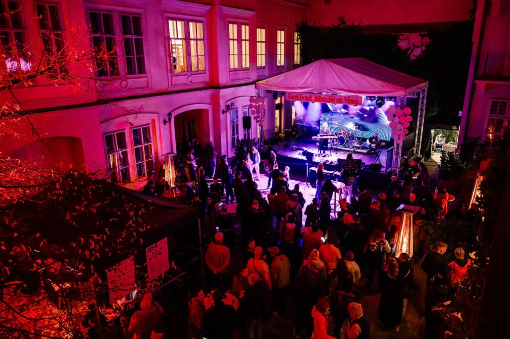 Nádvorie sv. Jána Nepomuckého s hlavným pódiom a vystupujúcimi, pred pódium stojí publikum. Pohľad na nádvorie z balkóna, podvečer.