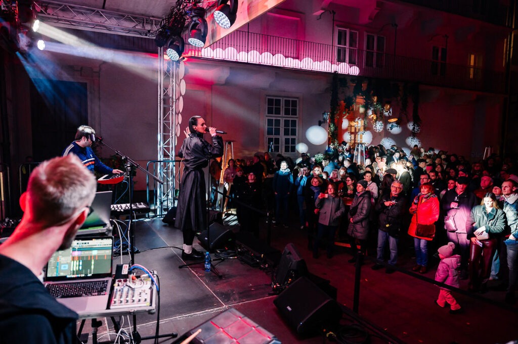 Koncert Ovarius, pohľad zboku na pódium, pred pódiom stoja diváci a diváčky